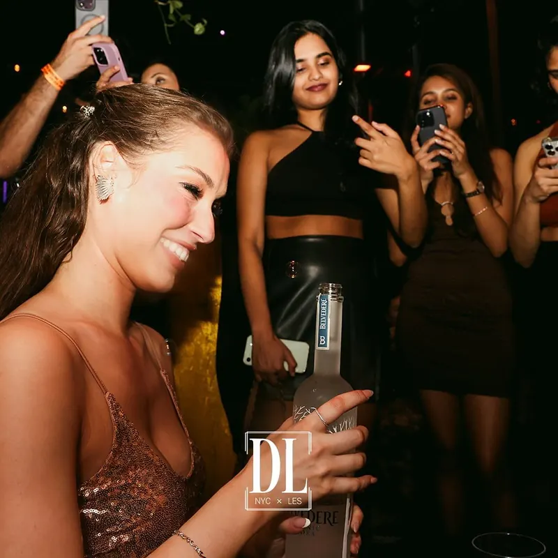 A birthday guest with a sparkler bottle and friends filming