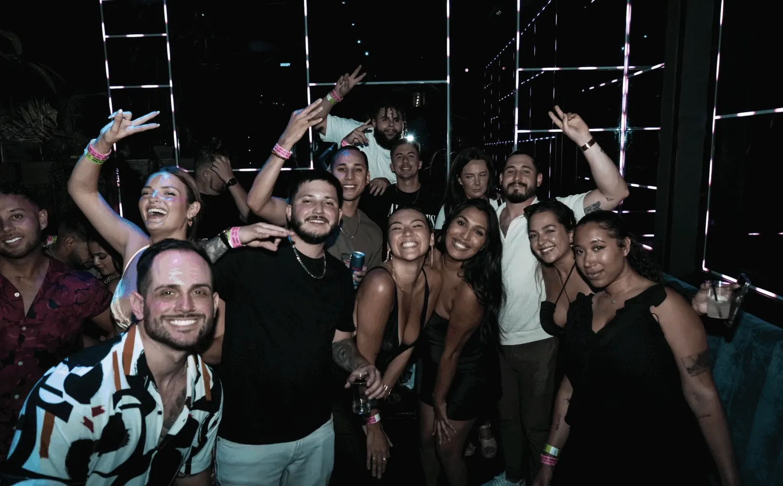 A big crew throwing peace signs under the LED frames at The DL